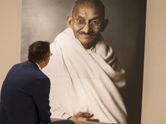 Premier Daniel Andrews sits in front of a portrait of Mahatma Gandhi in Delhi
