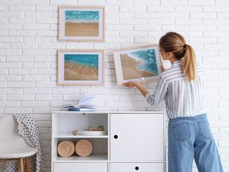 A woman hanging art prints on a wall