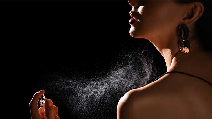A woman spraying scent on her body